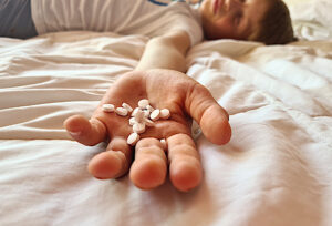 Child lies on bed with overdose of pills. Drug poisoning in children